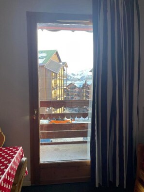 A wooden door with a frosted glass panel, leading to a balcony with a view of a mountainous landscape and a lake. - Risoul 1850 • Apartment for 4–5 people • Skis on your feet • Swimming Pool & Sauna (Risoul)