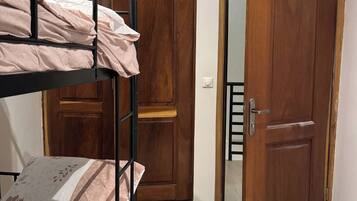 A room with a bunk bed, wooden wardrobe, and a door.