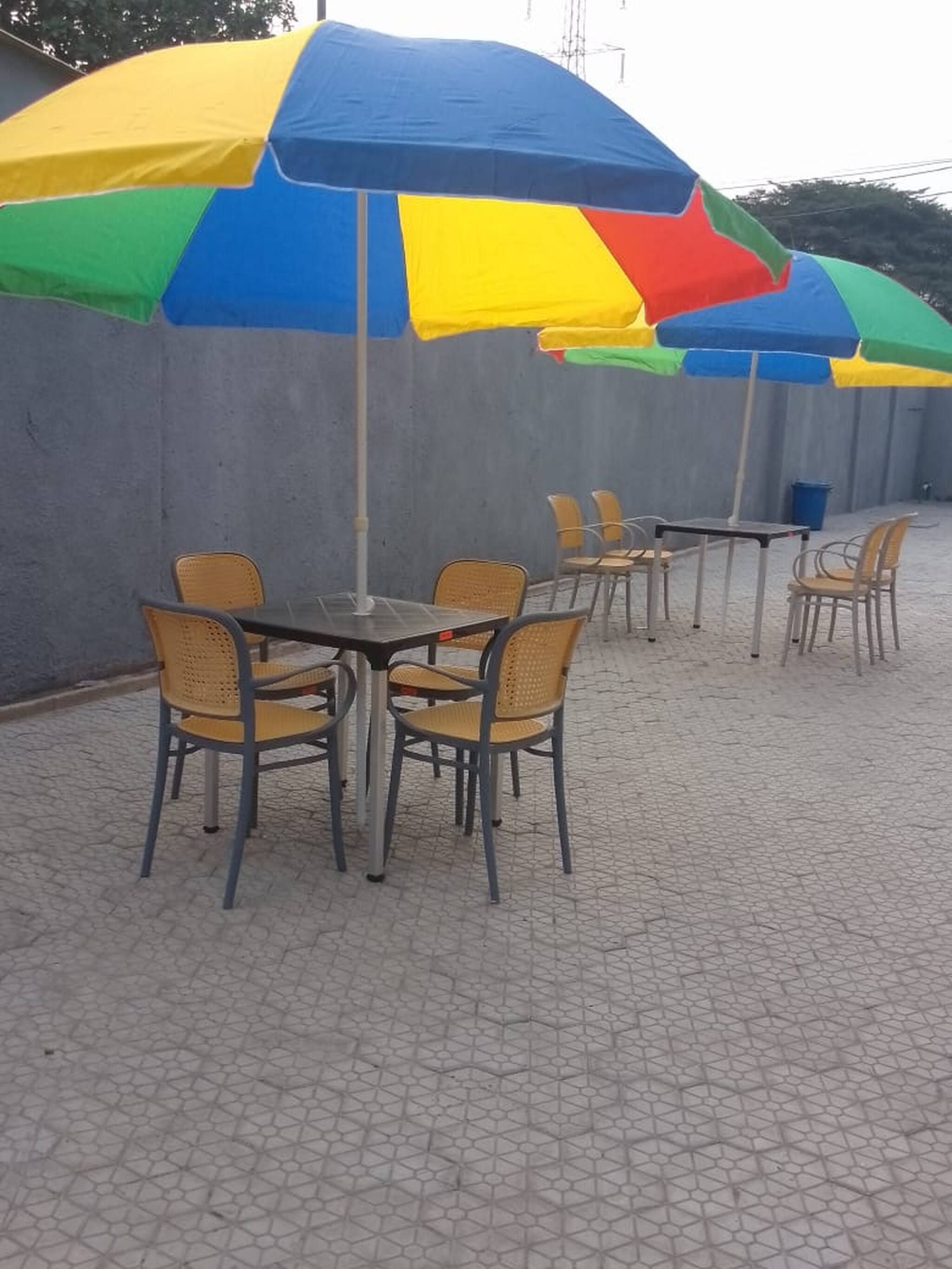 Outdoor seating with a large umbrella, wicker chairs, and a tiled floor.