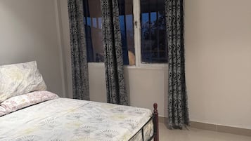 Ein Schlafzimmer mit einem Bett, Vorhängen, einem Fenster und einer Klimaanlage.