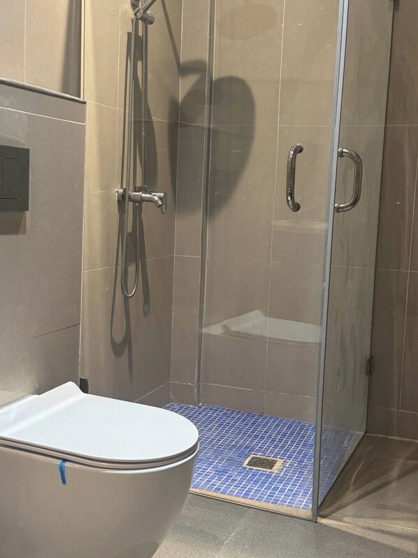 A bathroom with a glass-enclosed shower, a toilet, and a tiled floor. - Duplex nr 3 in Bandal (Kinshasa)