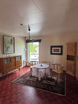 Ein Zimmer mit einem runden Tisch, Stühlen, einem Schrank und einem Teppich.