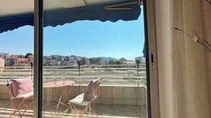 A balcony with a table and chairs, a view of a cityscape, and a clear sky. - Beautiful 2 bedroom terrace and parking (Cannes)