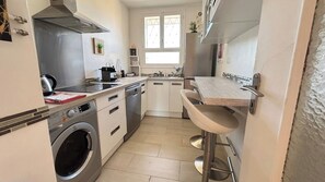 A compact kitchen with a washing machine, a sink, and a bar stool. - Beautiful 2 bedroom terrace and parking (Cannes)