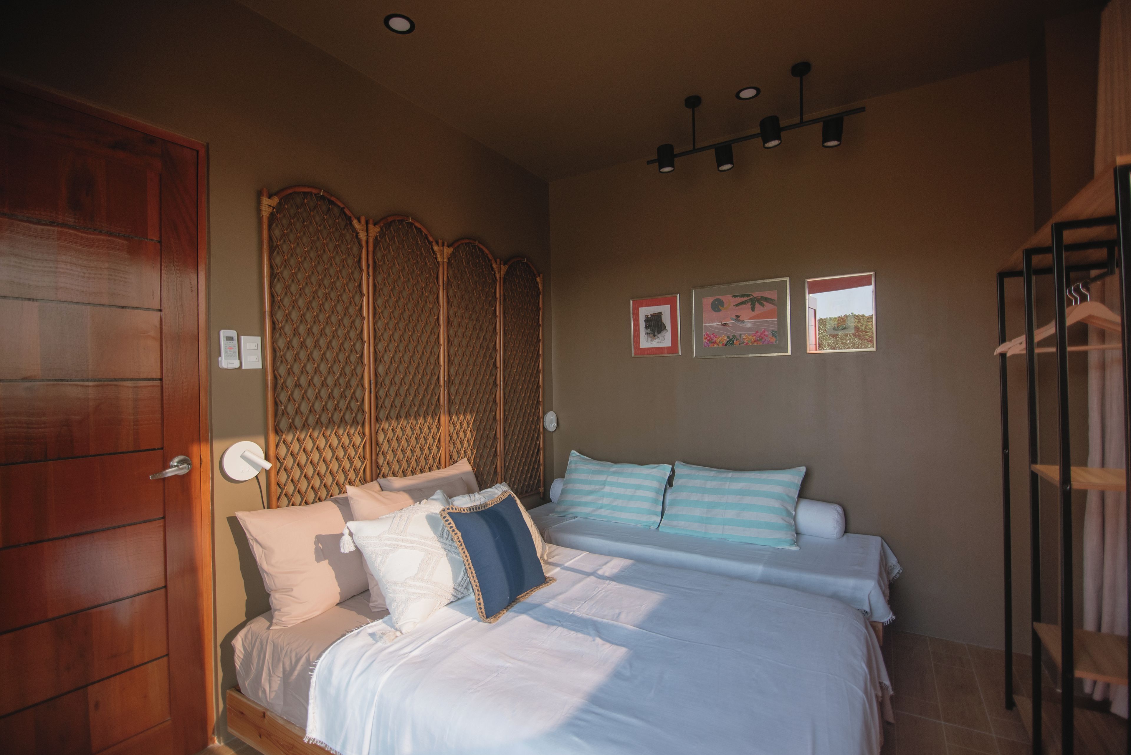 Un dormitorio con cama, una puerta de madera, una lámpara de pared y un accesorio de luz en el techo.