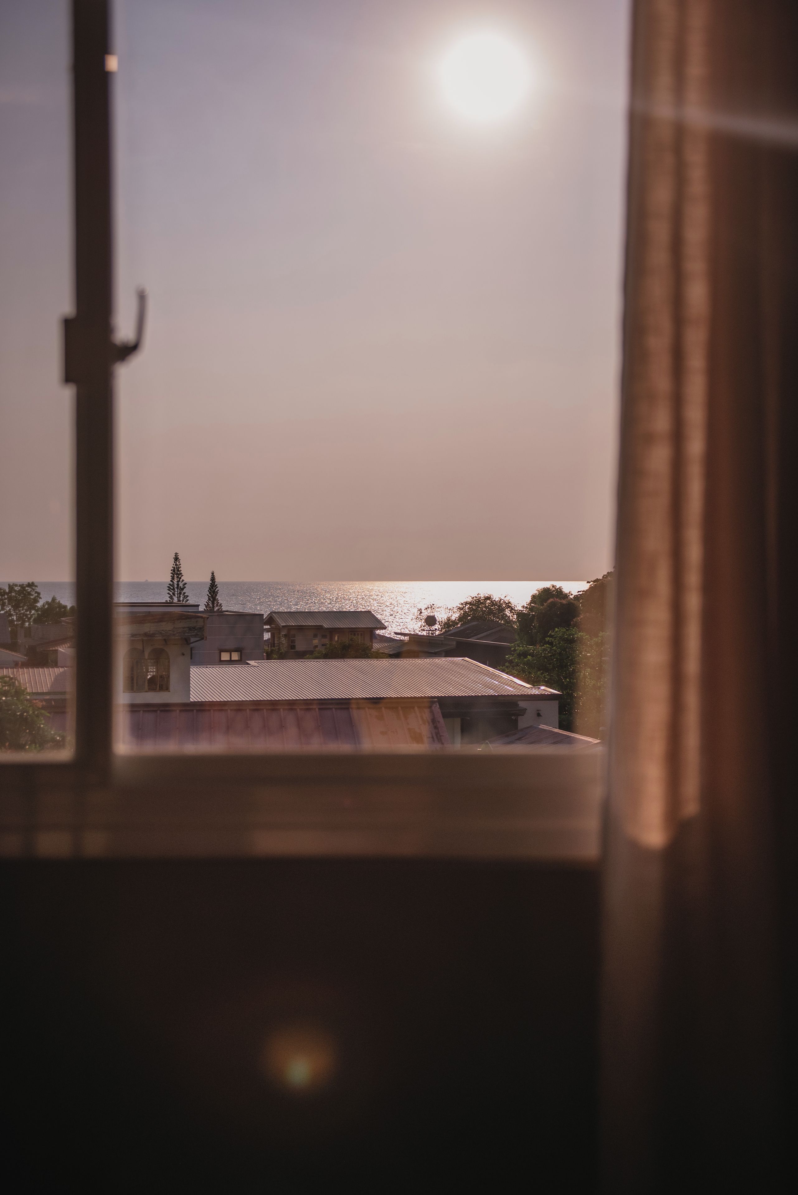 A view through a window with a building in the foreground and a body of water in the background.