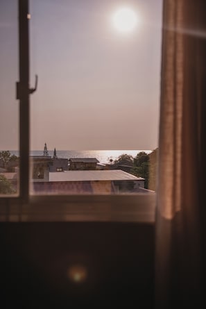 A view through a window with a building in the foreground and a body of water in the background. - 1BR Stylish Seaview Apartment Near The Beach with WiFi (San Fernando City)