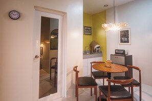 A dining area with a round table and four chairs, a kitchen with a microwave, and a clock on the wall. - 1BR Stylish Seaview Apartment Near The Beach with WiFi (San Fernando City)