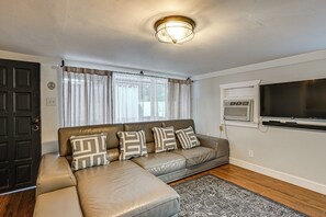 A living room with a leather sofa, patterned cushions, a television, and a ceiling light fixture. - 3 Mi to Dtwn! Cozy Tampa Home Base (Tampa)
