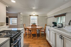 A kitchen with a stove, oven, dining table, chairs, and a coffee maker. - 3 Mi to Dtwn! Cozy Tampa Home Base (Tampa)