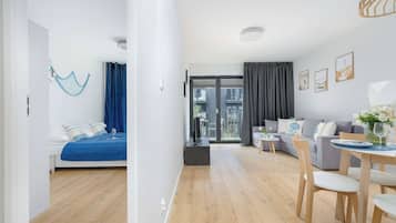 Una sala de estar moderna con un sofá, una mesa de comedor con sillas, un televisor y un balcón con vistas.