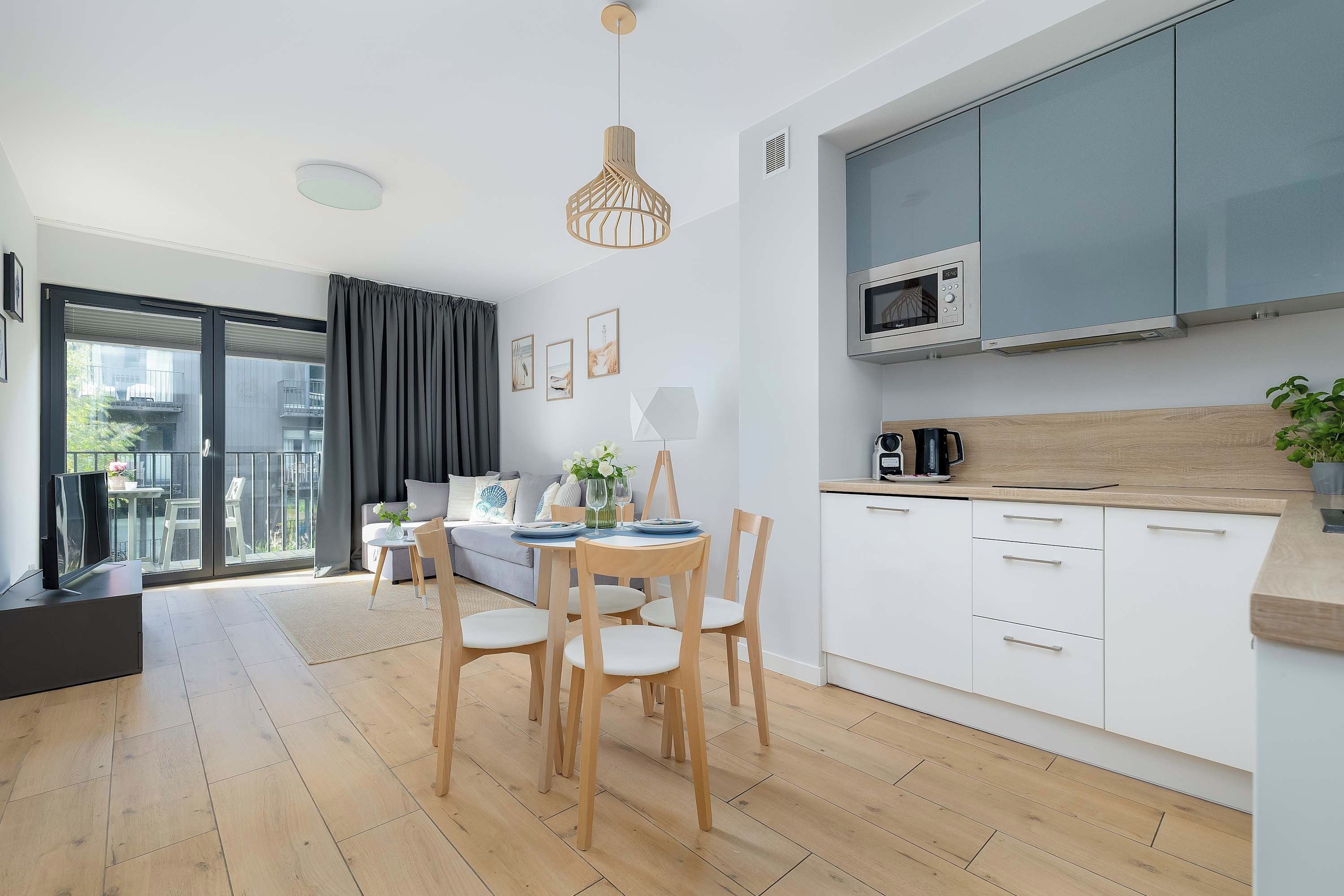 Une cuisine moderne avec des meubles blancs, un four à micro-ondes et un plan de travail en bois.