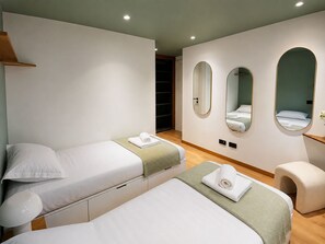 A hotel room with two beds, a small seating area, and a mirror on the wall. - Chalet Bois du Lac 8p/4r (Chamonix-Mont-Blanc)