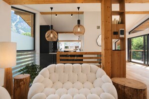 Un interior moderno con una butaca redonda y capitonada, vigas de madera e iluminación colgante.