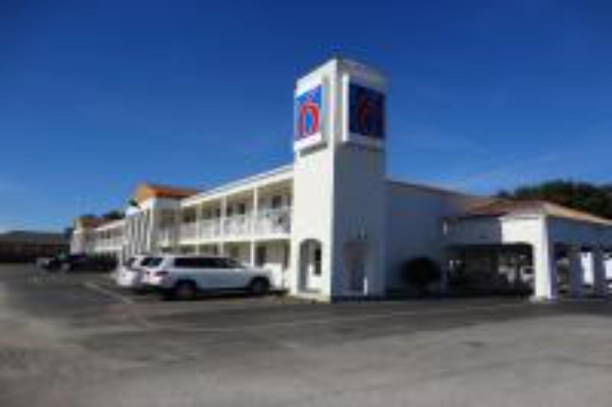A building with a prominent sign, a parking lot, and a few cars.