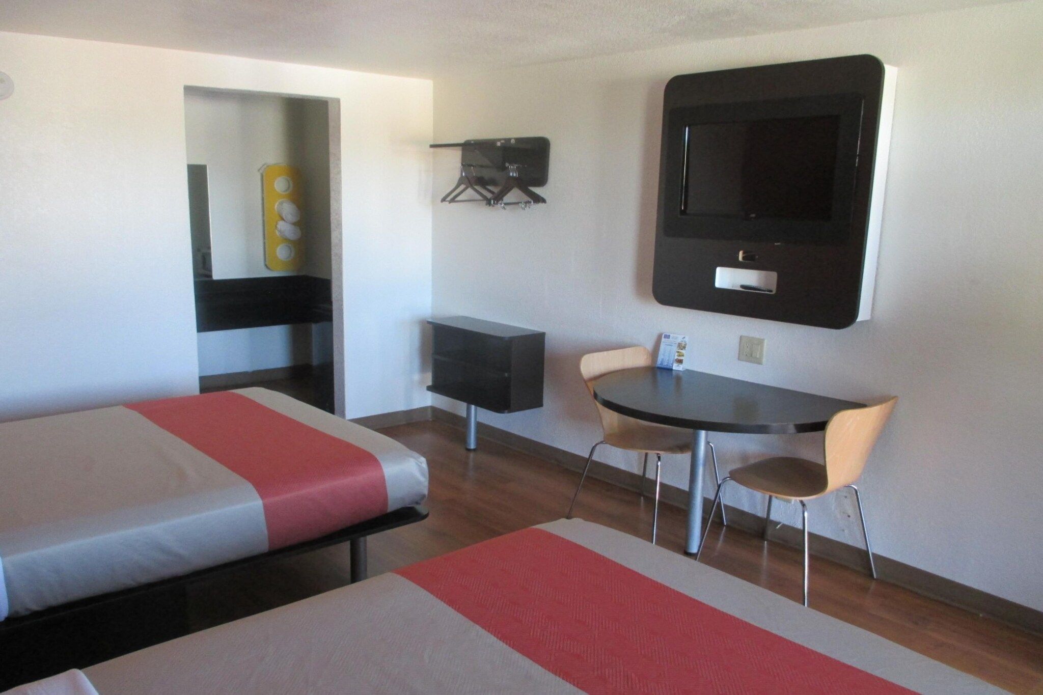 A hotel room with two beds, a desk, a chair, a TV, and a small cabinet.
