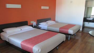 Two beds with white and pink bedding, a nightstand, a wall clock, and a bathroom with a sink and mirror.
