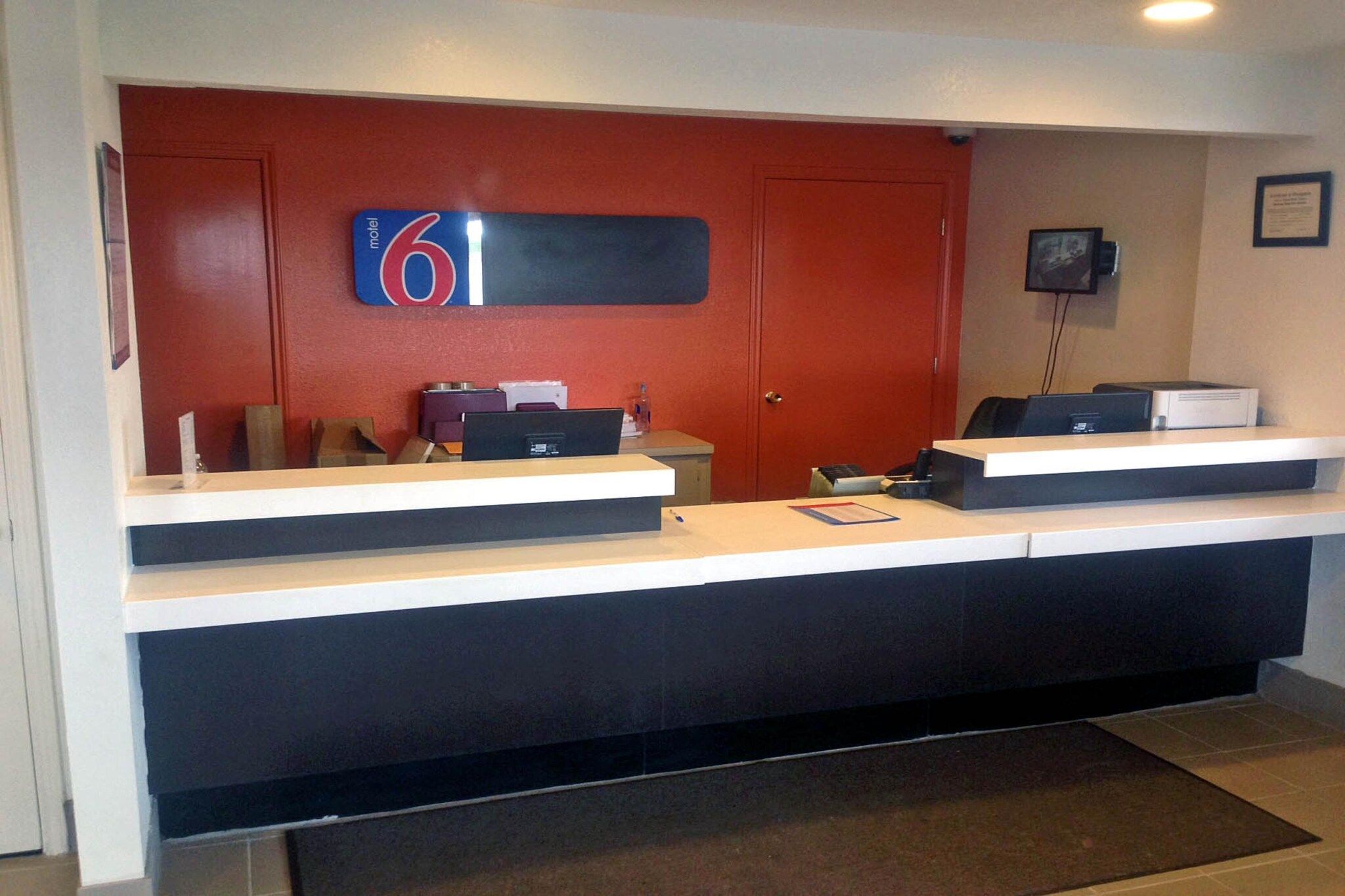 A reception desk with a digital display, a telephone, and a computer.
