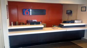 A reception desk with a digital display, a telephone, and a computer.