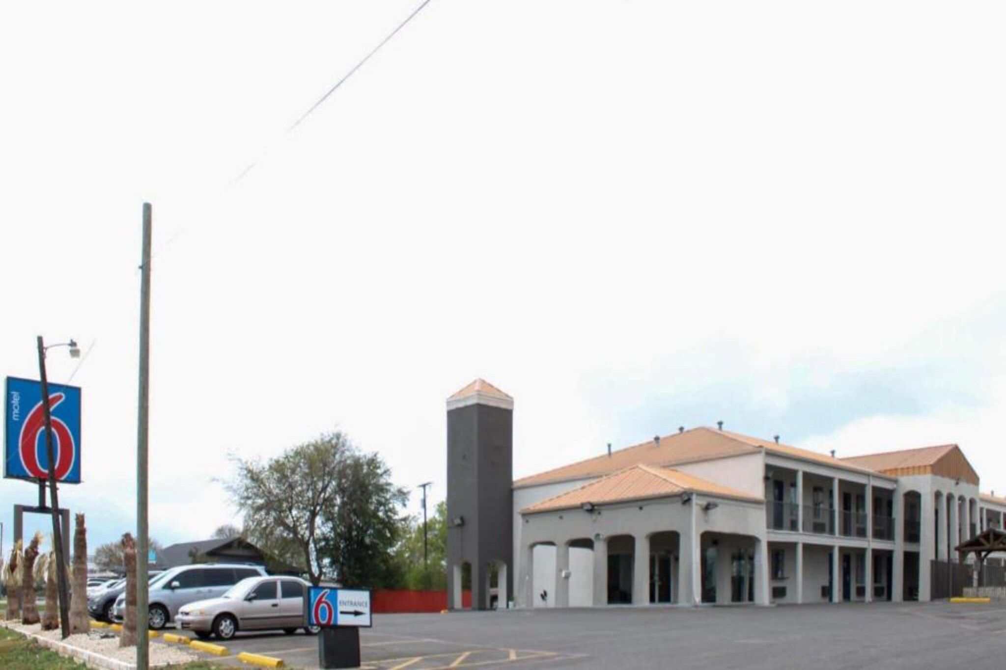 A building with a central tower, multiple windows, and a parking lot.