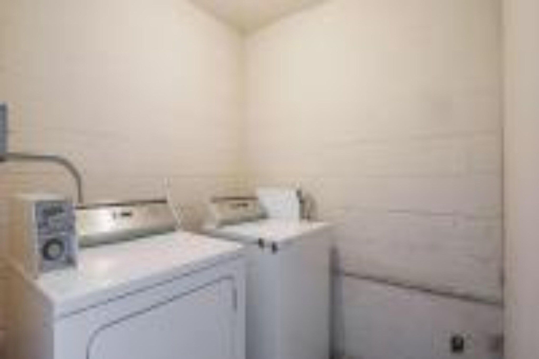 A laundry room with two washing machines and a dryer.