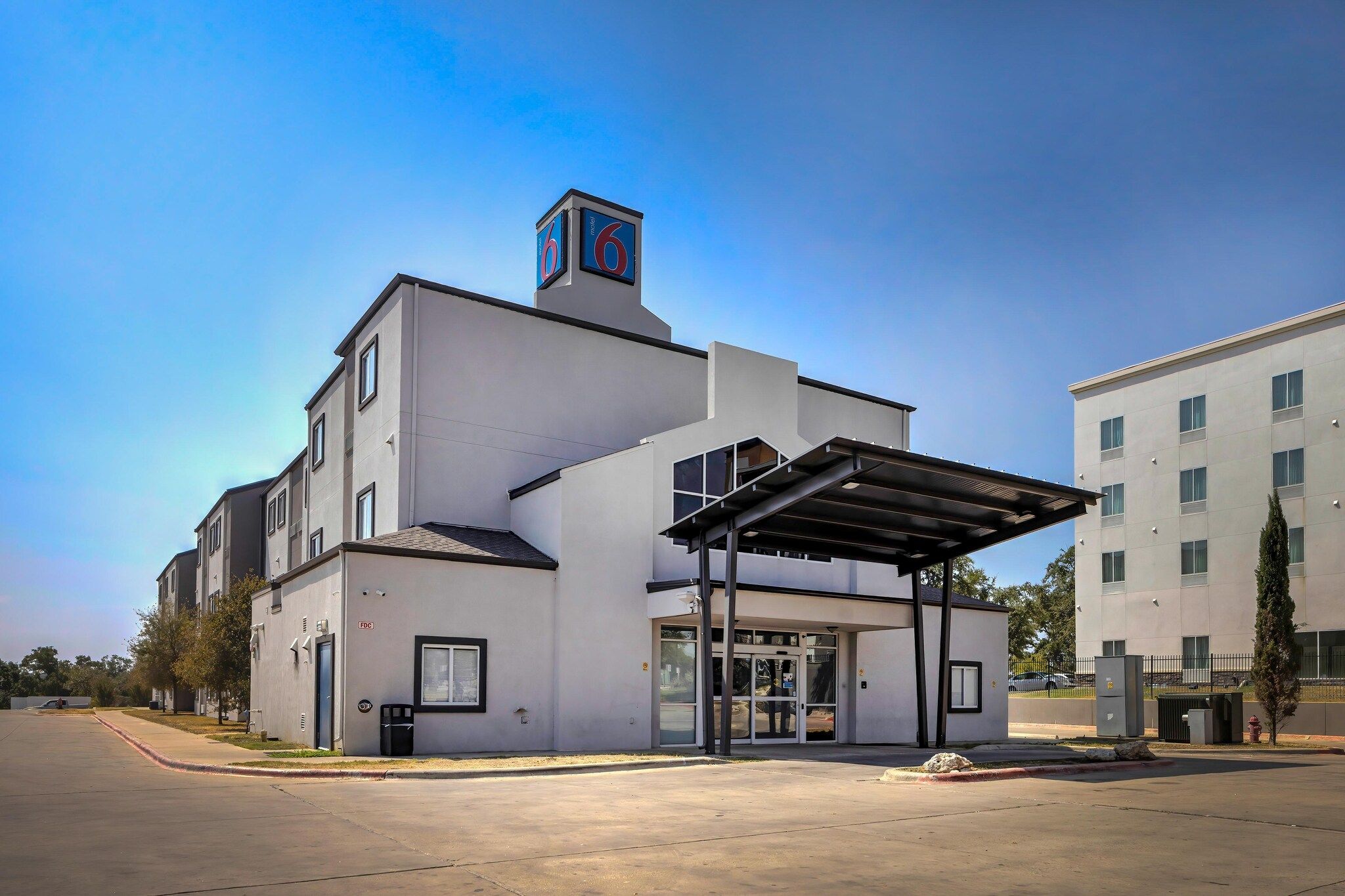 A modern building with a covered entrance, a prominent sign with the number 6, and a clear sky.