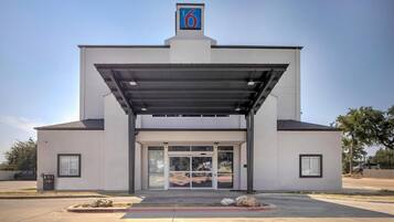 A motel with a modern design, featuring a covered entrance and a prominent number sign.