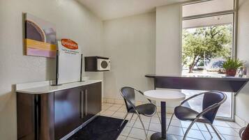 A small kitchenette with a microwave, a coffee station, and a window with a view of trees.