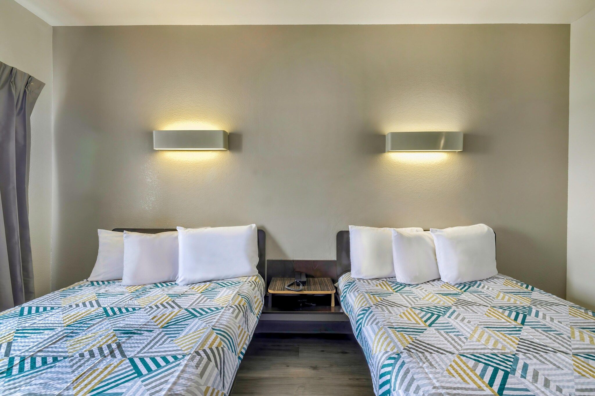 Ein Hotelzimmer mit zwei Einzelbetten, einem Nachttisch und Wandlampen.