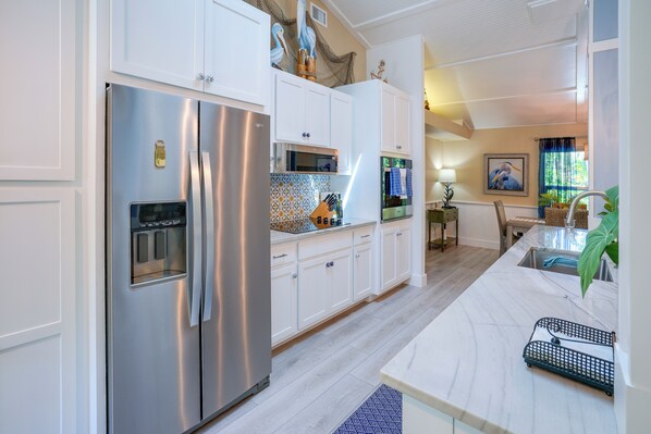A modern kitchen with stainless steel appliances, white cabinetry, and a marble countertop. - 4 minute walk to Private Beach Plus a Private Pool (Vero Beach)
