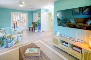 Ein Wohnzimmer mit einer Couch, einem Couchtisch, einem Bücherregal und einem großen Gemälde an der Wand.