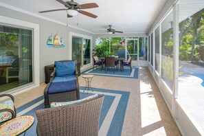 Ein überdachter Patio-Bereich mit Korbmöbeln, einem Deckenventilator und Blick ins Freie.