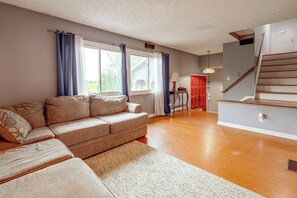 Ein Wohnzimmer mit einer Couch, einem Teppich, einer Treppe und einer Tür.