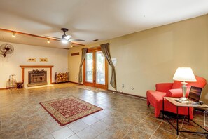 A spacious living room with a fireplace, a red sofa, a coffee table, and a ceiling fan. - Working Travelers Welcome! Cozy New Albany Escape (New Albany)