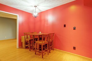 A dining area with a wooden table and chairs, a chandelier, and a red wall. - Working Travelers Welcome! Cozy New Albany Escape (New Albany)