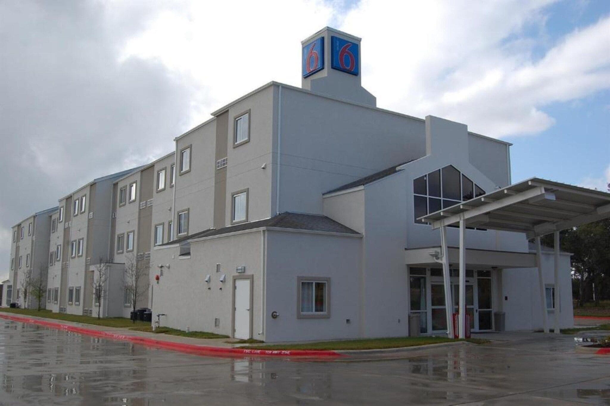 Un edificio de varios pisos con techo plano, un acceso cubierto y un letrero llamativo con el número '6'.