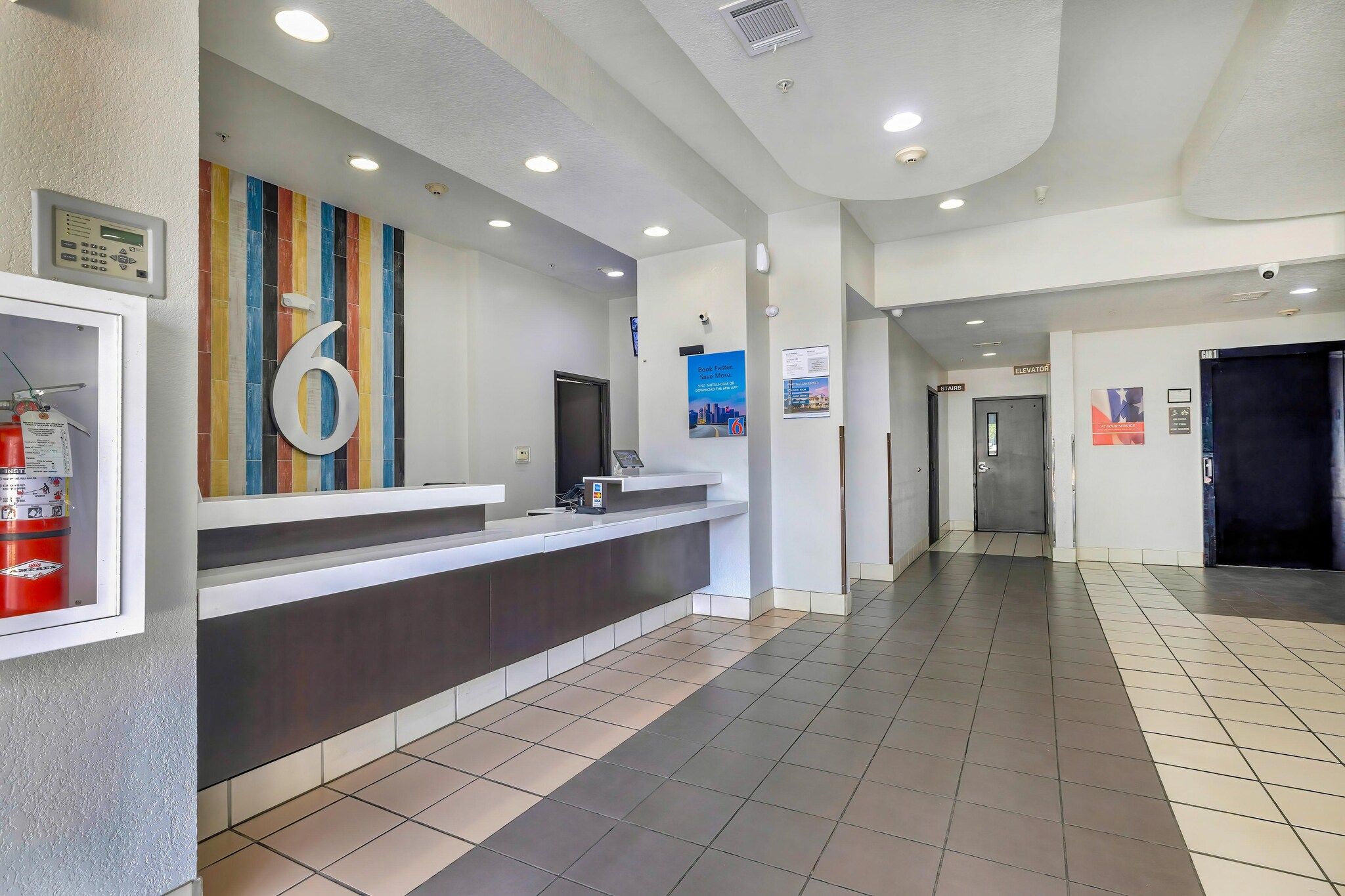 A reception area with a counter, a fire extinguisher, and a large number '6' on the wall.