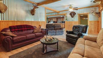 A living room with a fireplace, a sofa, a coffee table, and a dining area in the background.