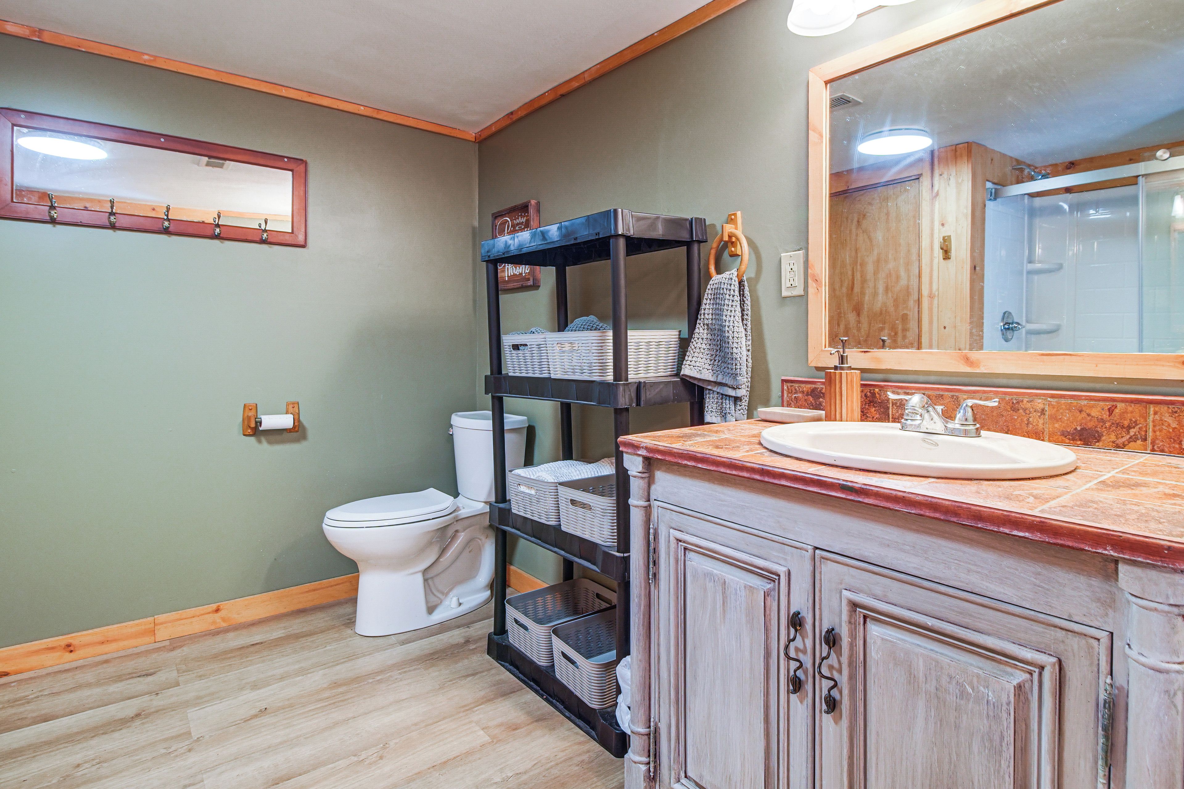 Une salle de bain équipée de toilettes, d’un lavabo, d’un miroir et d’étagères avec des paniers.