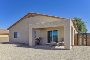 Uma casa com varanda coberta, churrasqueira e porta de correr.