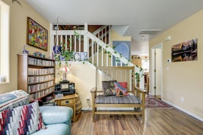 Een gezellige woonkamer met een boekenkast, een bank, een salontafel en een trap met uitzicht op een andere kamer.
