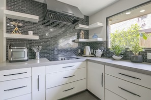 Eine Küche mit Schwarz-Weiß-Spritzschutz, einem eingebauten Backofen und einem Fenster mit Blick auf Grünflächen.