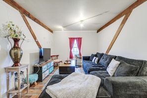 A living room with a sofa, a television, and a decorative vase.
