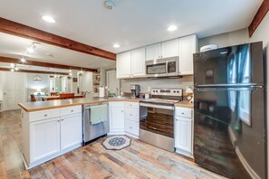 A modern kitchen with white cabinetry, stainless steel appliances, and a wooden floor.