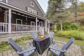 A porch with a covered seating area, a sign reading 'The Porch,' and a view of a wooded area.