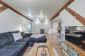 Un salon moderne avec un canapé, une table basse, un téléviseur et une cheminée.