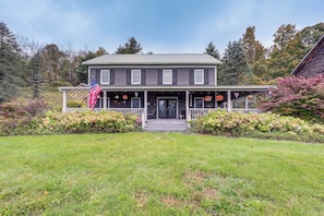 A two-story house with a front porch, a flag, and a well-maintained garden. - Retreat < 1 Mi to Otsego Lake & Opera’s House! (Cooperstown)