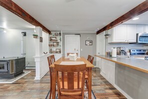A modern kitchen with white cabinetry, a wooden dining table, and a built-in oven.
