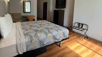 A hotel room with a bed, a desk, a chair, a TV, and a window.