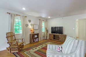 A living room with a wooden TV stand, a sofa, a patterned rug, and a wooden chair. - 3 Mi to Dtwn Blue Ridge! Family Home w/ Fire Pit (Blue Ridge)